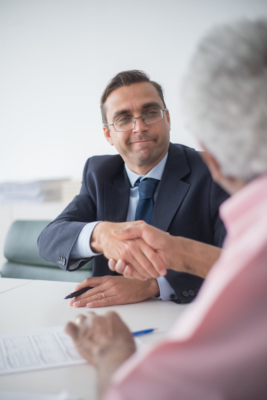 Man buying an online man in black suit jacket wearing eyeglasses shaking hands with a man