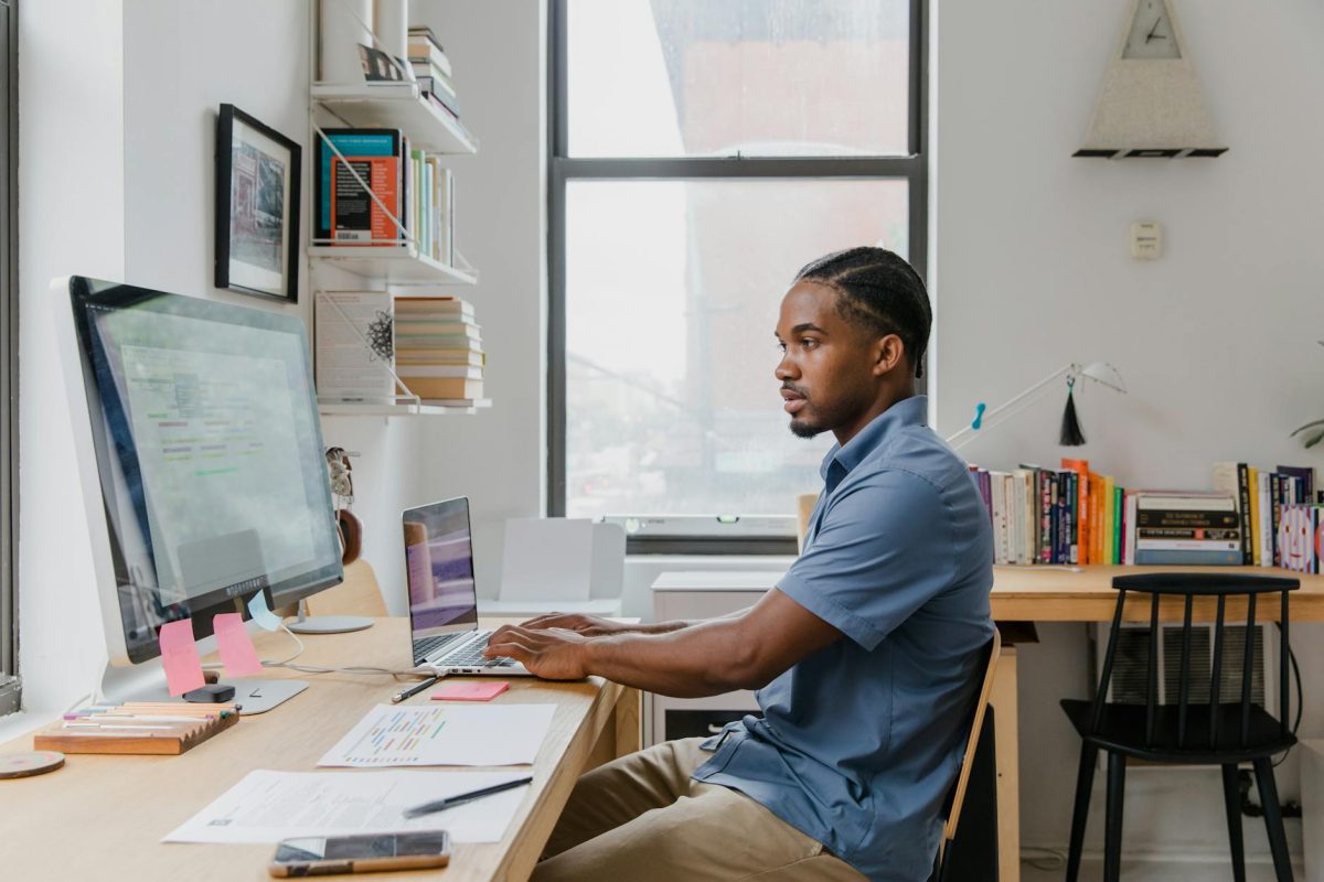 A man working at a desk with computers in an office for Software Developers and Programmers.